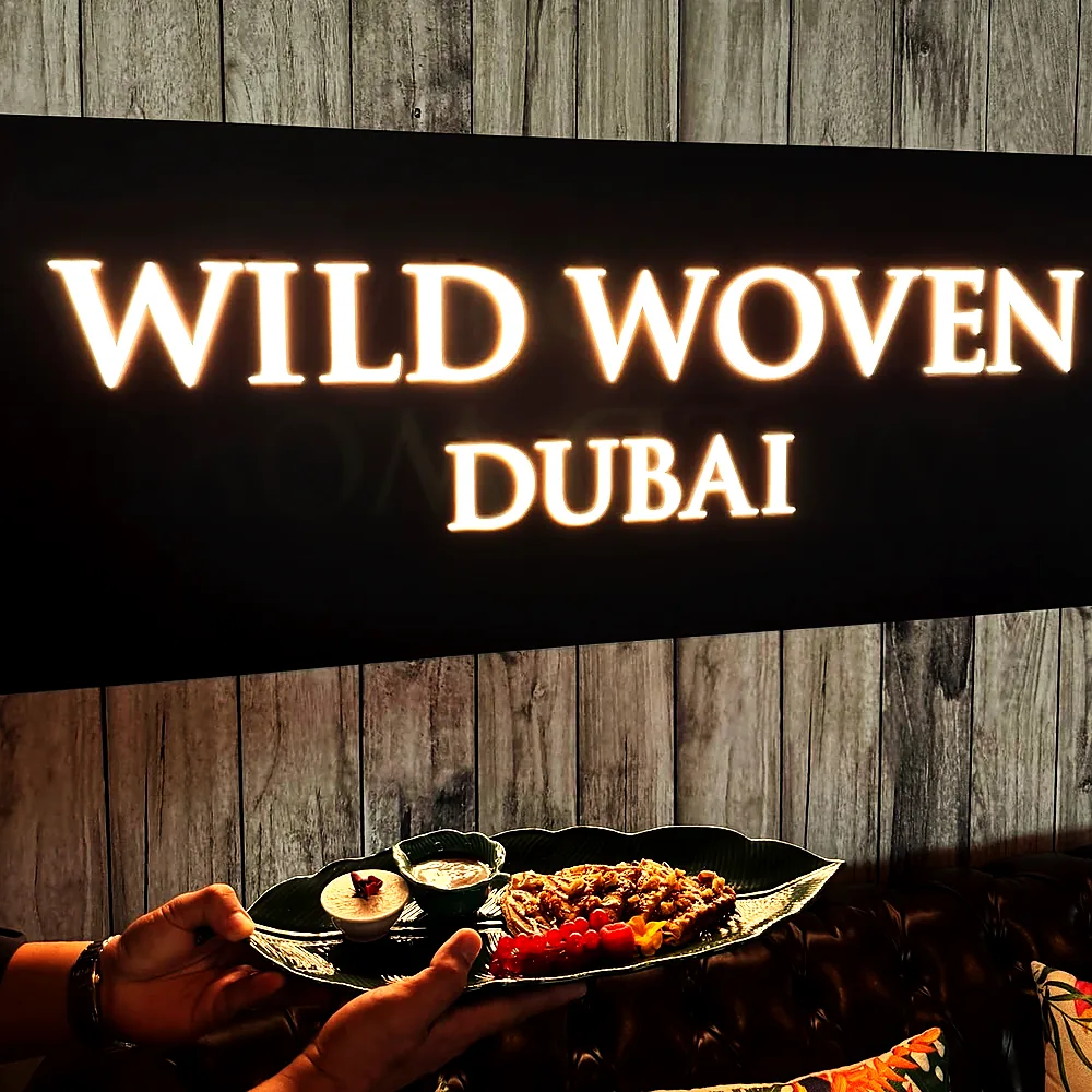 A sharing platter carried out beneath the illuminated Wild Woven Dubai sign