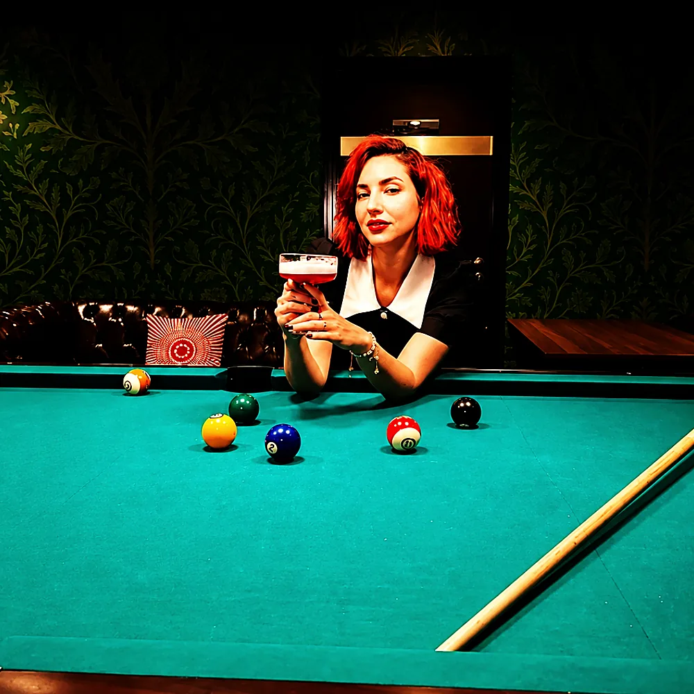 A guest with a drink at the billiards table