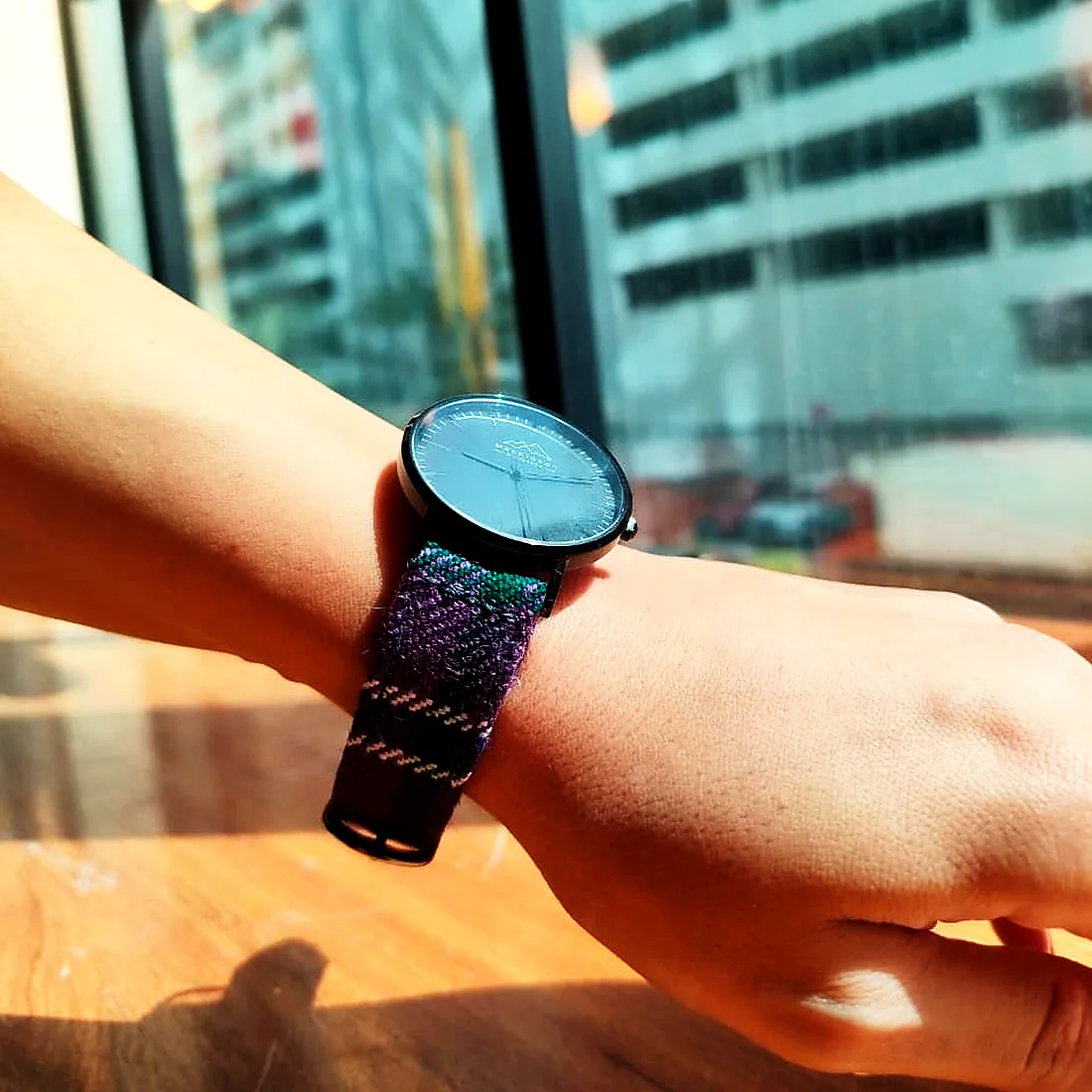 A watch on a woven tweed strap, worn at the window