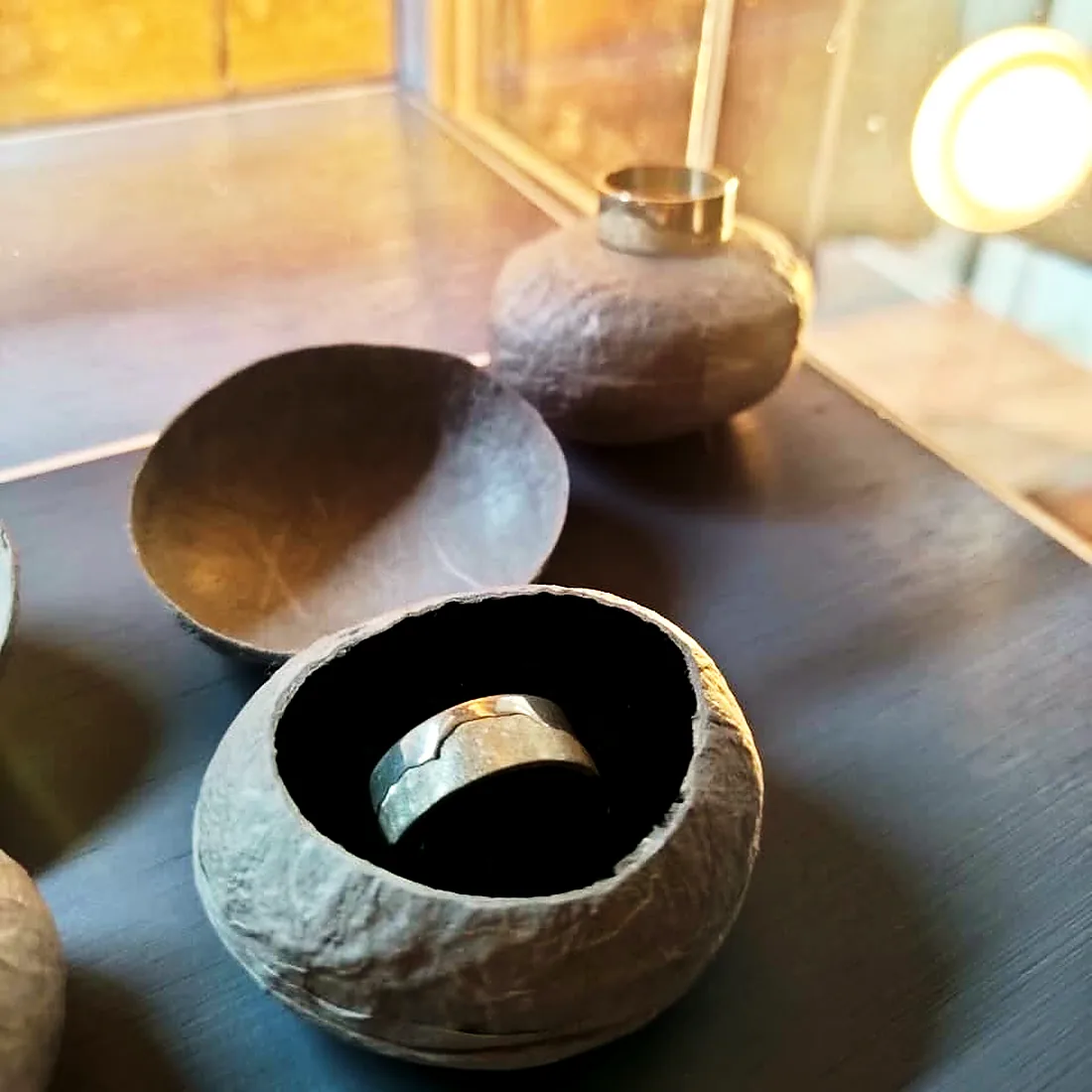 Hand-thrown stone vessels holding a silver ring