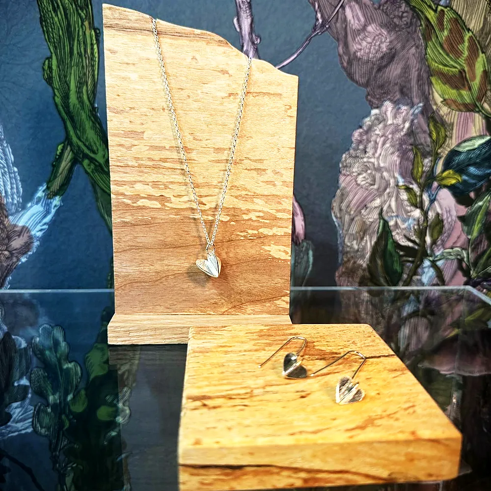 A silver necklace displayed on a wood block