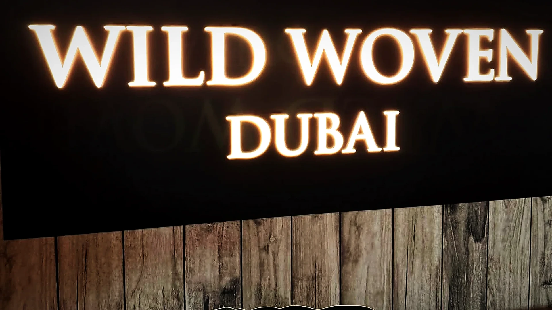 A sharing platter carried out beneath the illuminated Wild Woven Dubai sign