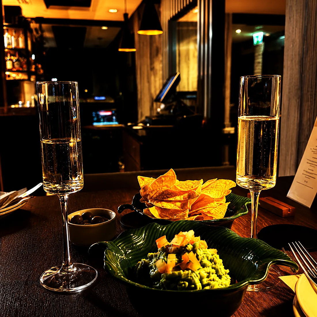 Guacamole, nachos and two glasses of fizz